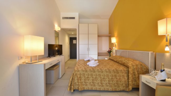 Camera con letto matrimoniale e parete gialla.