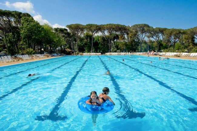 Grande piscina all'aperto con persone che nuotano.