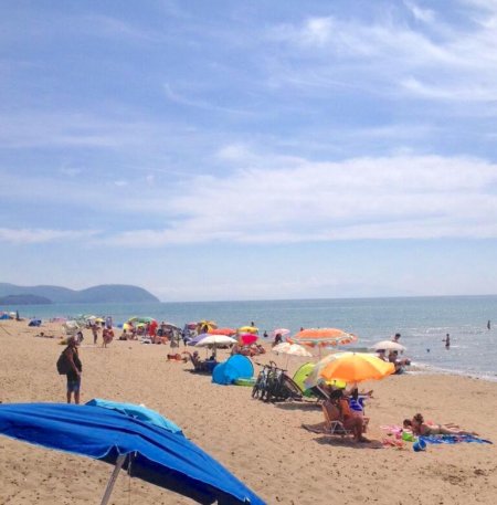 Spiaggia affollata di ombrelloni colorati e persone.