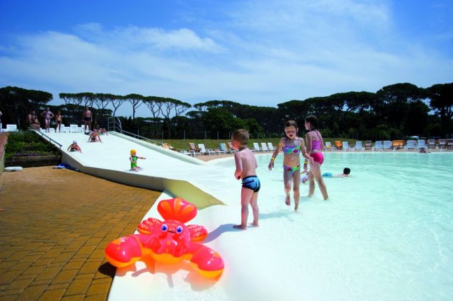 Bambini che giocano in una piscina con uno scivolo.