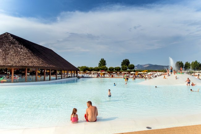 Piscina con fontana, persone e capanna di legno.