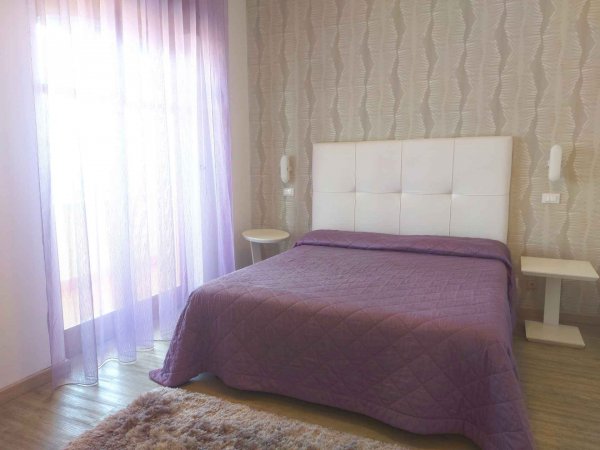 Camera da letto con tenda e copriletto viola.