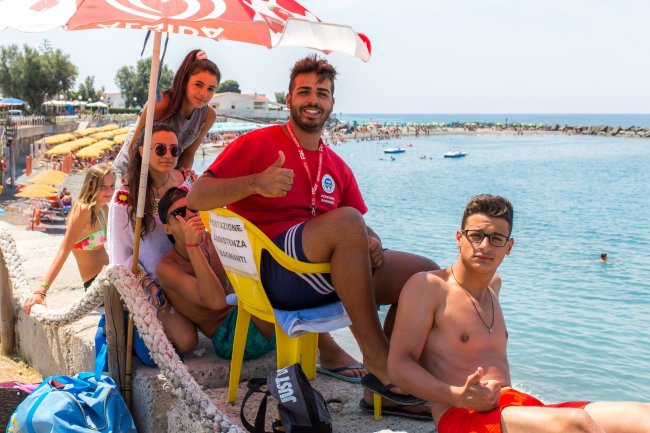 Persone sorridenti sotto un ombrellone sulla spiaggia.