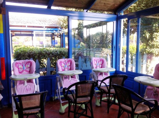 Tre seggioloni rosa per bambini vicino a finestre in un'area luminosa.