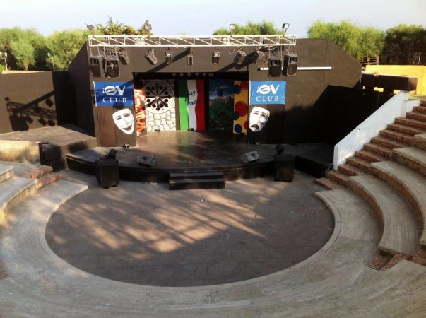 Un palco all'aperto con sedili semicircolari e maschere teatrali dipinte.