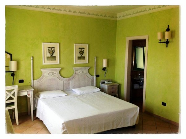 Camera d'albergo con pareti verdi e letto matrimoniale.