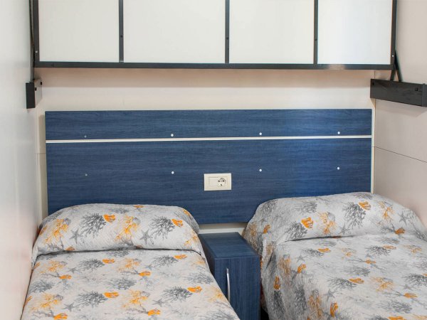 Due letti singoli con testiera blu e lenzuola con motivi floreali gialli e grigi.