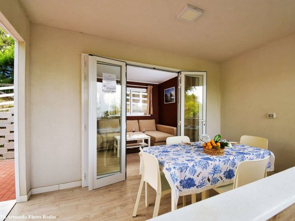 Sala luminosa con tavolo apparecchiato, vista su un salotto interno.