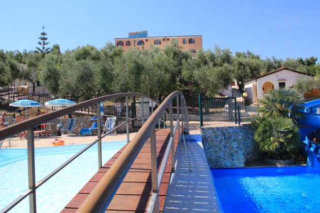 Piscina con un ponte e ombrelloni blu in un parco acquatico.