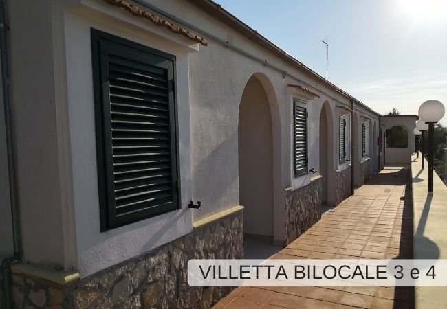 Villetta con persiane verdi e portico.
