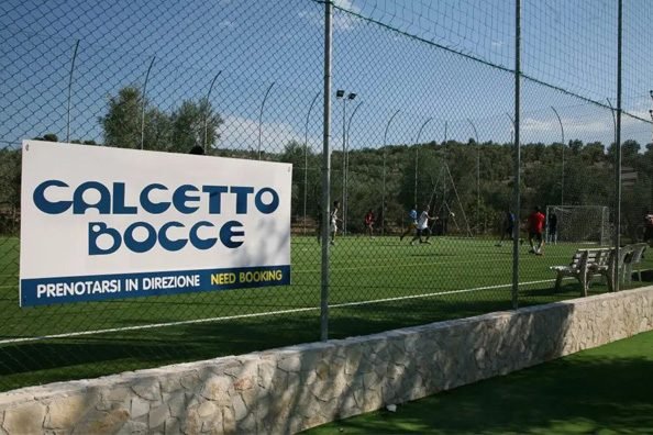 Campo da calcetto all'aperto con cartello e rete di recinzione.