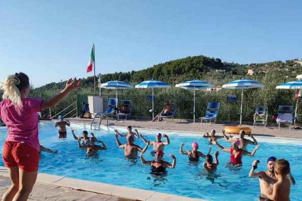 Lezione di acquagym in piscina con persone e istruttrice.