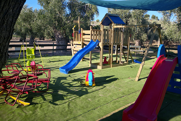 Parco giochi con scivoli e altalene colorate.