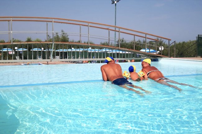 Tre persone in una piscina all'aperto di giorno.