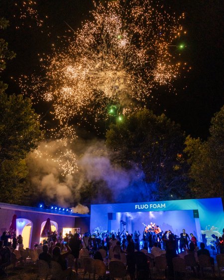 Fuochi d'artificio sopra un palco con luci blu.