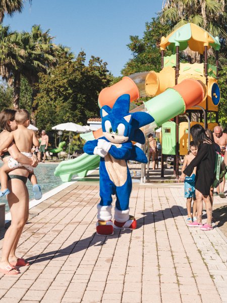 Mascotte blu vicino a piscina e scivoli.