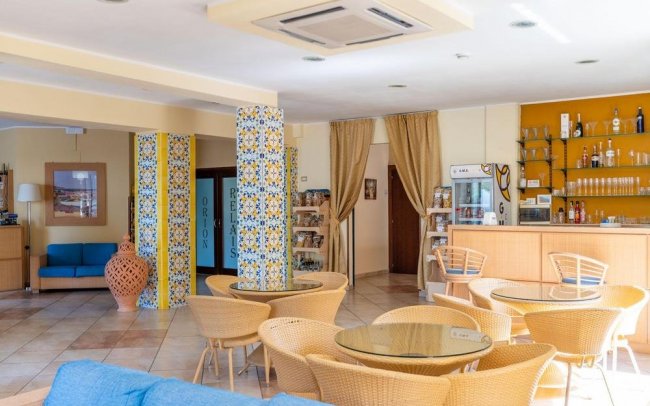 Caffetteria con tavoli, sedie in vimini e bar.