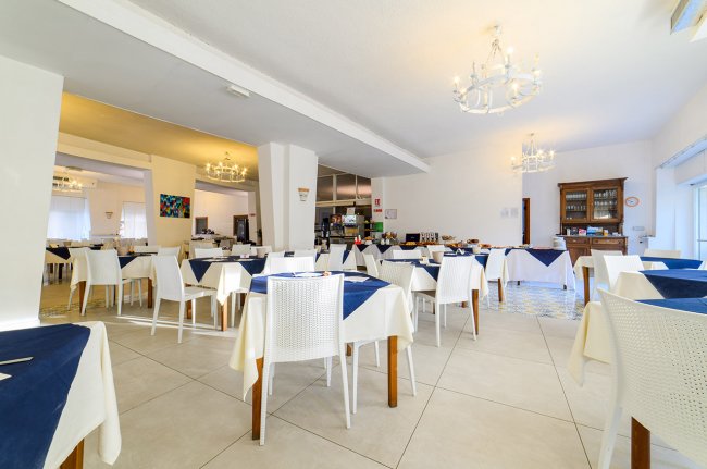 Sala da pranzo con tavoli bianchi e decorazioni blu.