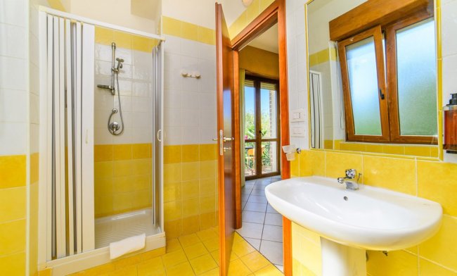 Bagno con doccia, lavabo e piastrelle gialle.