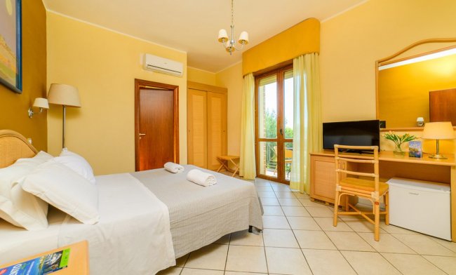 Camera con letto, scrivania e accesso al balcone.