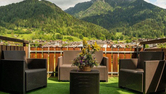 Terrazza con poltrone di vimini e vista sulle montagne.