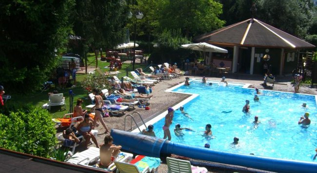 Una piscina affollata con persone che nuotano e si rilassano.