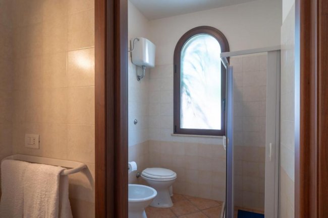 Bagno con doccia, finestra curva e asciugamani.
