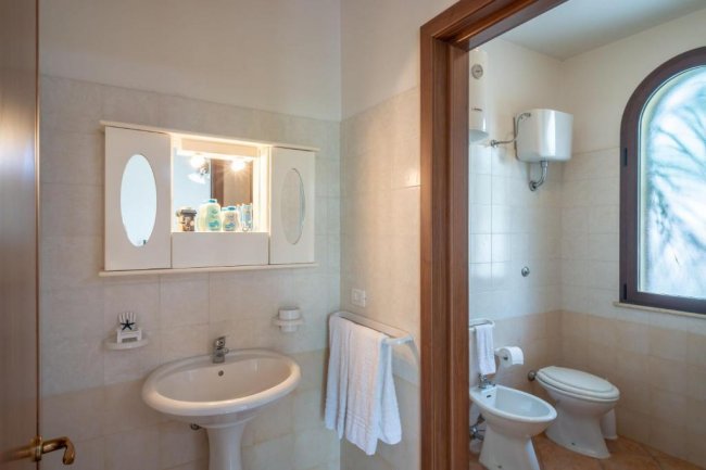 Lavabo con specchio e sanitari in bagno luminoso.