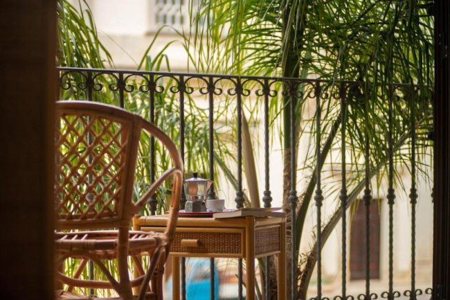 Balcone con sedia di vimini e tavolo.