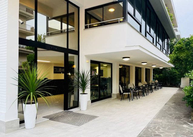 Facciata di hotel con veranda e sedie bianche.