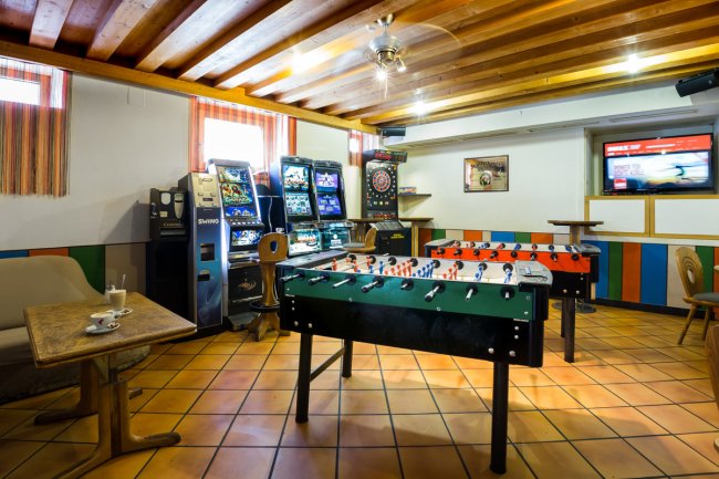 Sala giochi con calcetti, freccette e macchinette da gioco.