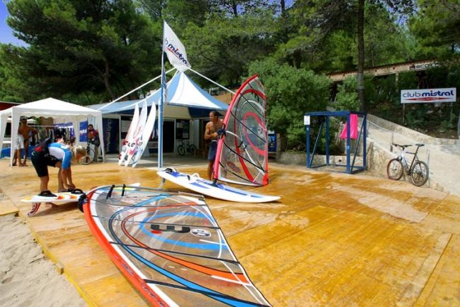 Tavole da windsurf su una piattaforma di legno, vicino a tende.