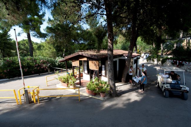 Edificio tra alberi con un cart da golf e persone.