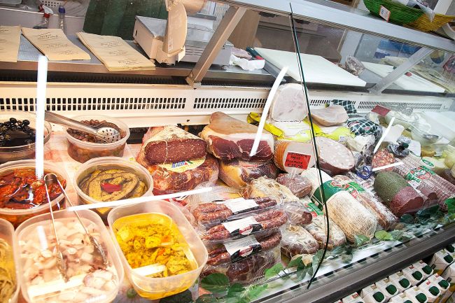 Banco frigo con salumi, formaggi e altri cibi.