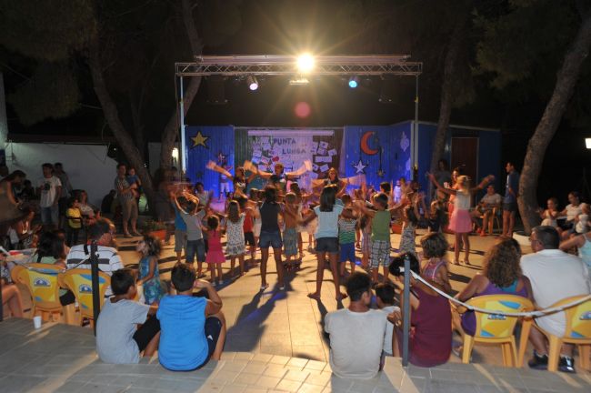 Spettacolo serale all'aperto con pubblico e bambini.