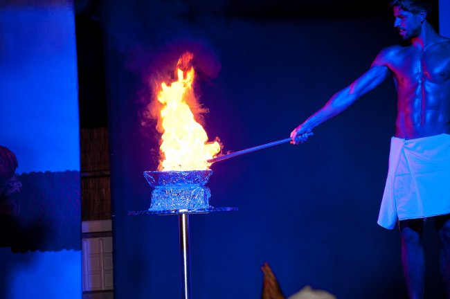 Persona in piedi accanto a un fuoco acceso su una pedana.