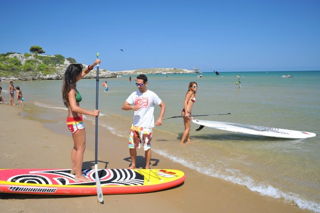 Persone con tavole da paddle sulla spiaggia.