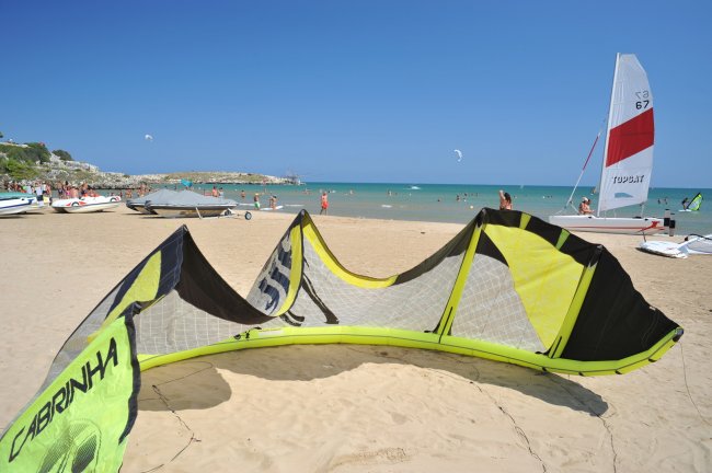 Spiaggia sabbiosa con aquilone volante giallo.
