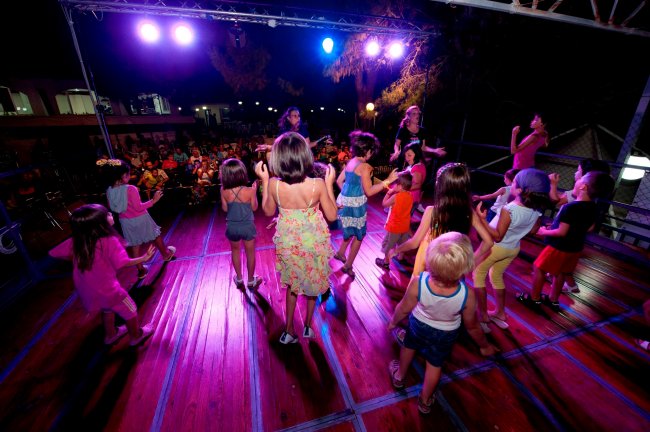 Bambini che ballano su un palco illuminato.