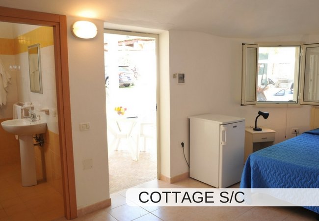 Stanza con finestra, frigo bianco e letto.