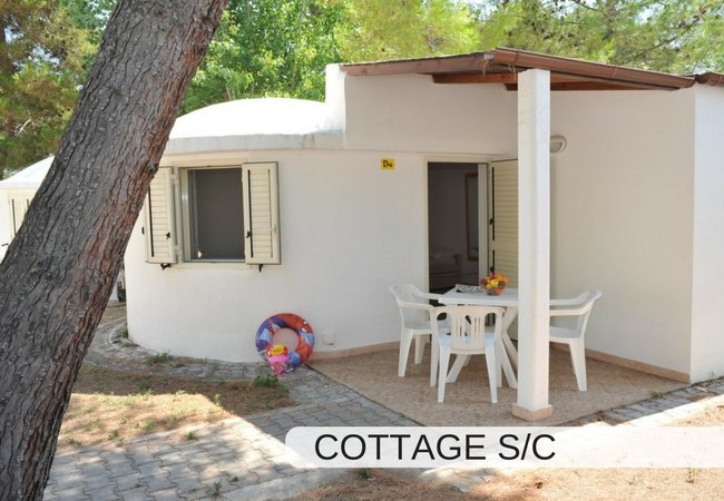 Cottage bianco con veranda e tavolo esterno.