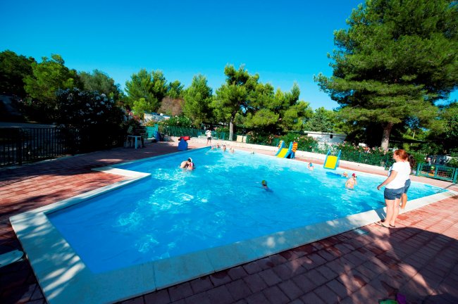 Piscina all'aperto con persone che nuotano.