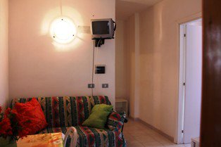 Salotto con divano, lampada e TV piccola.