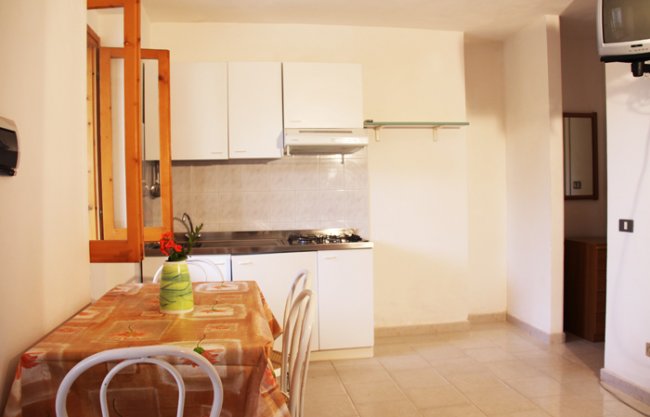 Cucina con tavolo apparecchiato e mobili bianchi.