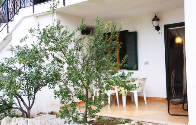 Terrazza con tavolo bianco e alberi circostanti.
