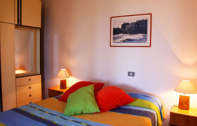 Camera da letto con letto colorato e due lampade.