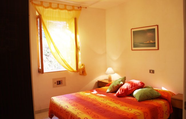 Camera da letto con letto colorato e tende gialle.