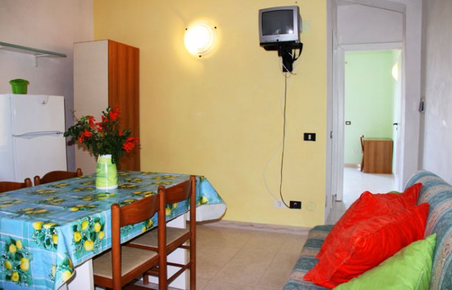 Cucina con tavolo coperto e divano colorato.