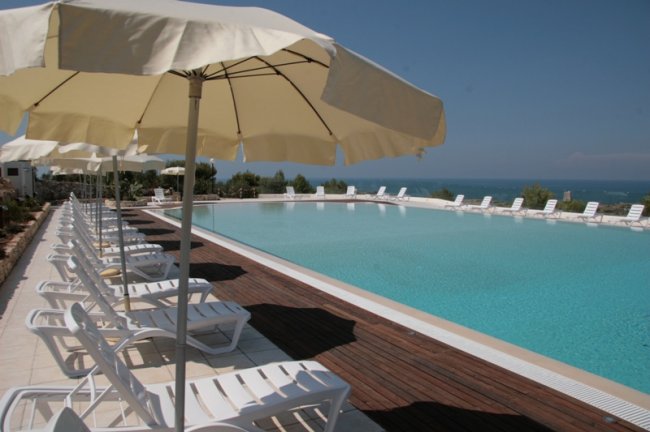 Piscina con lettini e ombrelloni in fila.