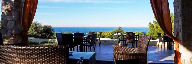 Terrazza con sedie e tavoli vista mare.